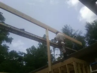 Carpenter setting a ridge beam over a new addition frame — Ice Dam Removal by Roofing Brothers in Bonfield