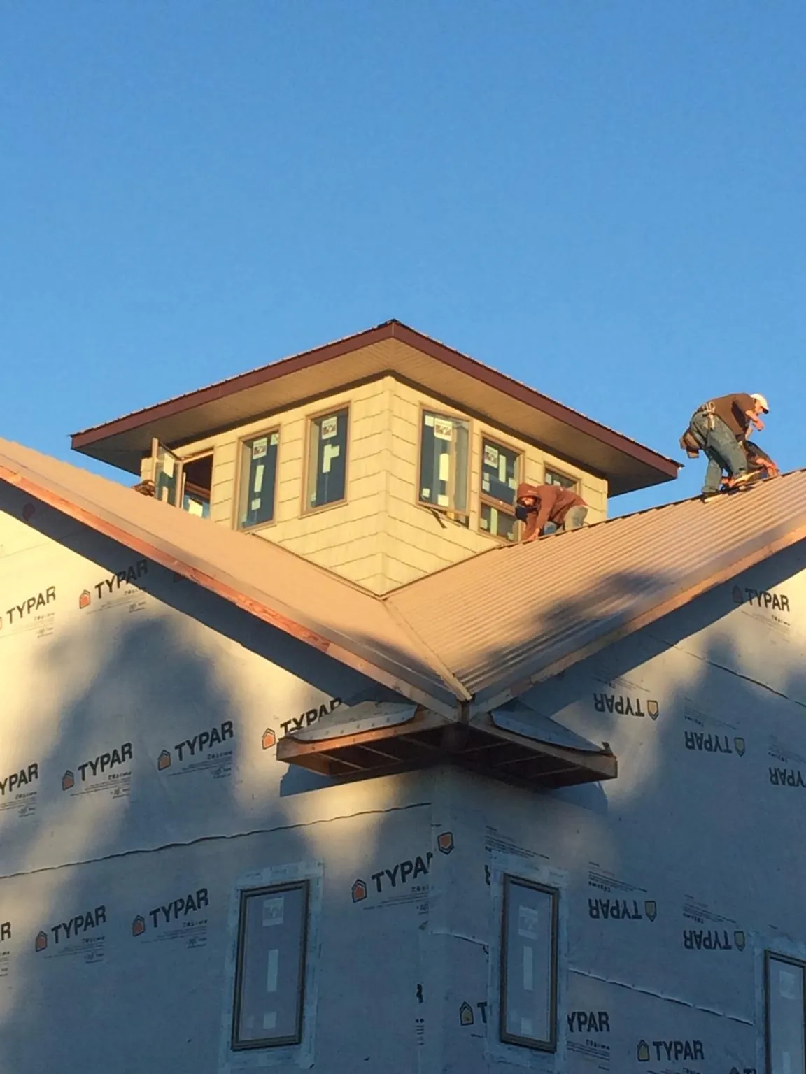 Roofers working around a rooftop cupola on a new metal roof at sunset — Roof Waterproofing in Bonfield by Roofing Brothers